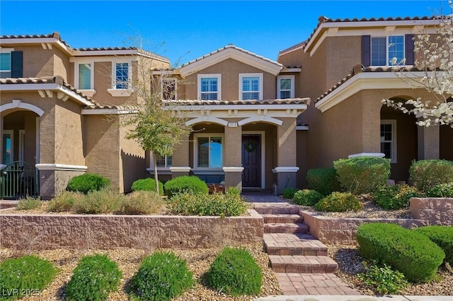 view of front of property featuring a porch, a tiled roof, and stucco siding