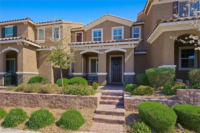 view of front of home with a tiled roof, covered porch, and stucco siding