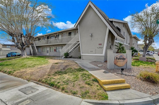 multi unit property featuring stairway, a front yard, and stucco siding