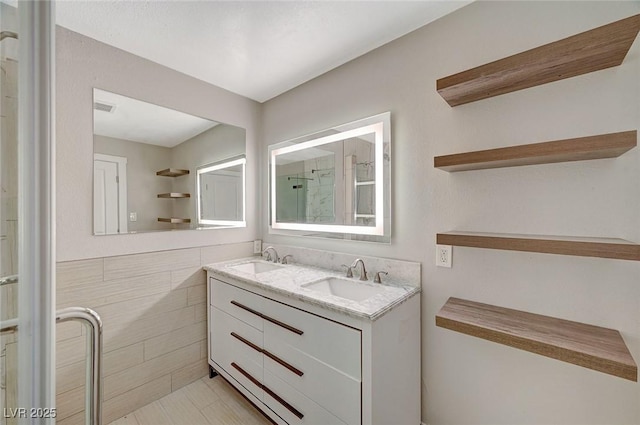 bathroom with tile walls, visible vents, a stall shower, and a sink