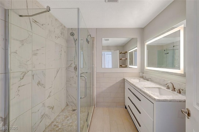 bathroom with double vanity, a stall shower, tile walls, and a sink