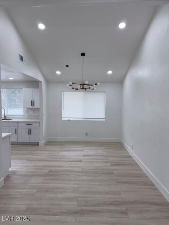 unfurnished dining area featuring a sink, baseboards, visible vents, and a chandelier