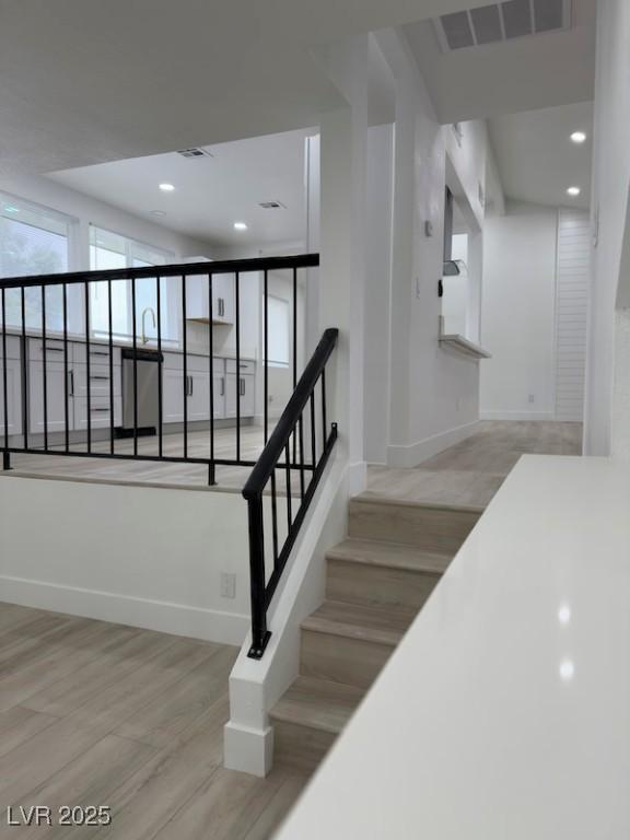 stairway featuring recessed lighting, wood finished floors, visible vents, and baseboards