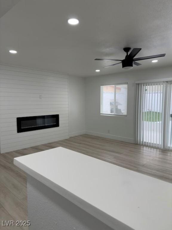 unfurnished living room with recessed lighting, light wood-type flooring, baseboards, and a fireplace