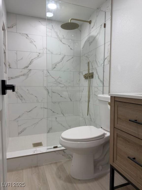 full bathroom featuring a marble finish shower, toilet, vanity, and wood finished floors