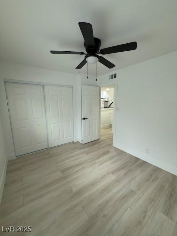 unfurnished bedroom with light wood-type flooring, visible vents, baseboards, and a closet