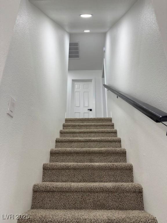 stairs with a textured wall and visible vents