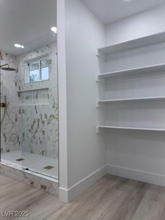 full bathroom featuring a walk in shower, baseboards, and wood finished floors