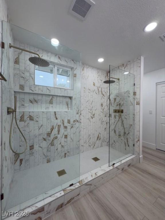 bathroom with visible vents, baseboards, walk in shower, and wood finished floors