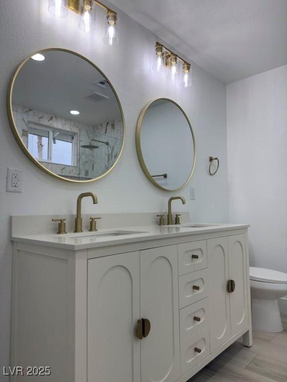 full bath with double vanity, wood finished floors, toilet, and a sink