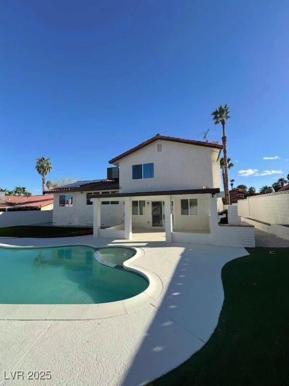 view of swimming pool with a pool with connected hot tub, a patio, and fence