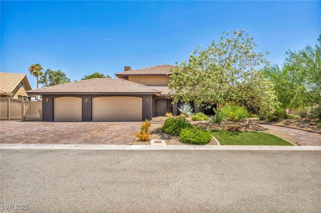 view of front of home with a tiled roof, an attached garage, driveway, and fence