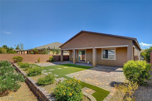 back of property with stucco siding, a patio, and a fenced backyard