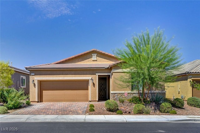 view of front of property with stucco siding, a tile roof, decorative driveway, and a garage