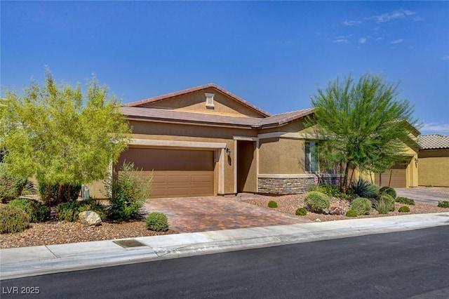 view of front of property featuring a tiled roof, stucco siding, a garage, stone siding, and driveway