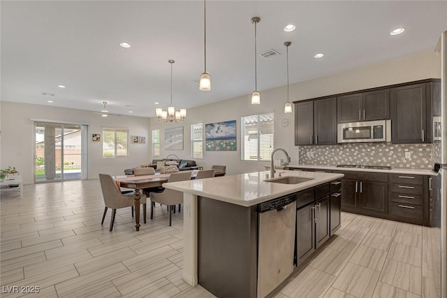 kitchen with a sink, stainless steel appliances, light countertops, dark brown cabinets, and open floor plan