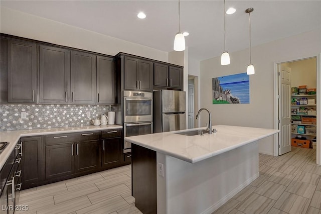 kitchen with wood finish floors, a sink, dark brown cabinetry, appliances with stainless steel finishes, and backsplash