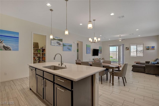 kitchen with a sink, light countertops, dishwasher, open floor plan, and a chandelier