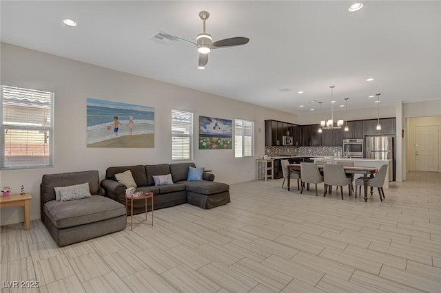 living area featuring recessed lighting and ceiling fan with notable chandelier