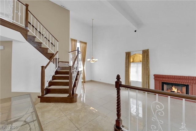 staircase featuring baseboards, beam ceiling, a towering ceiling, tile patterned floors, and a brick fireplace