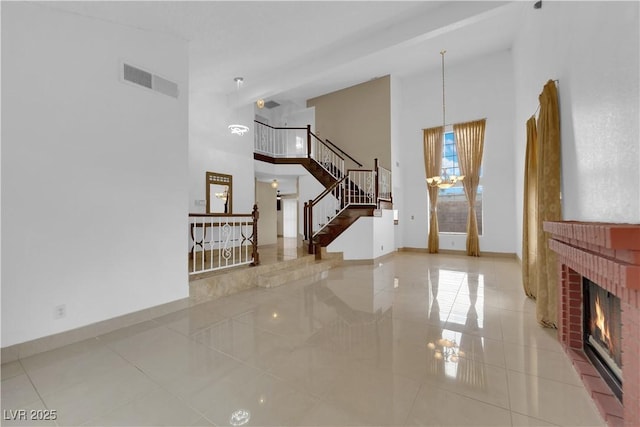 tiled living room with visible vents, a brick fireplace, baseboards, stairway, and a high ceiling