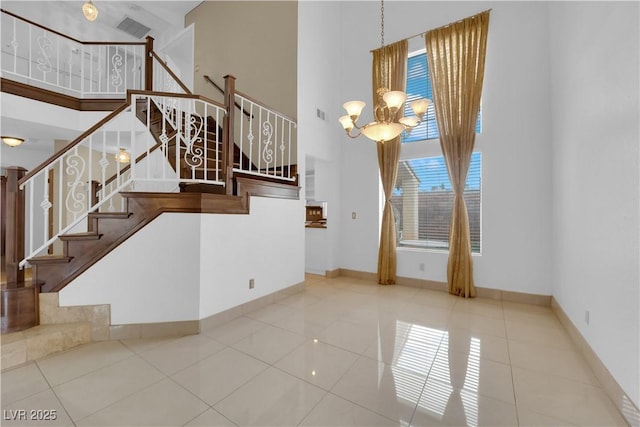 interior space with tile patterned floors, baseboards, a notable chandelier, and a towering ceiling