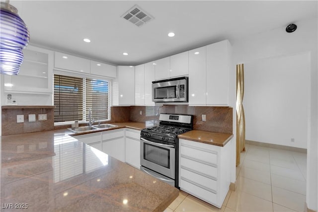 kitchen with visible vents, open shelves, a sink, decorative backsplash, and stainless steel appliances