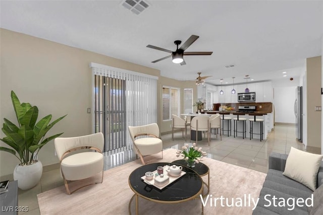 living area with light tile patterned floors, visible vents, baseboards, and ceiling fan