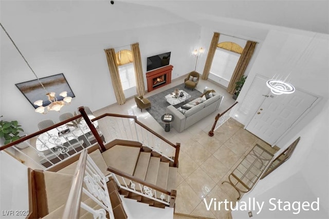 tiled living room with an inviting chandelier, stairway, and a warm lit fireplace