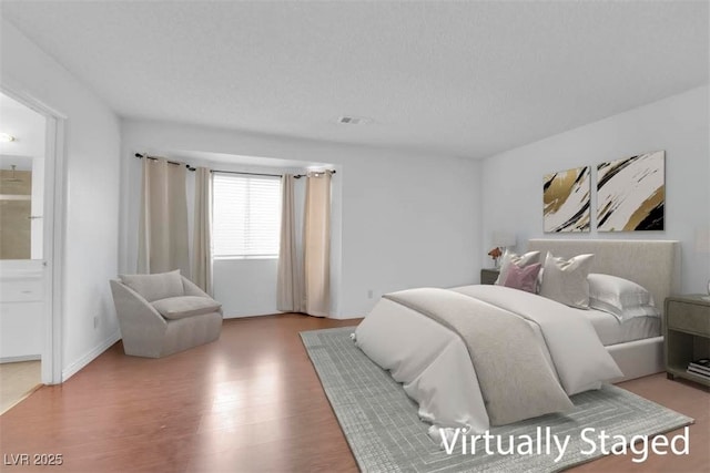 bedroom featuring wood finished floors, visible vents, and a textured ceiling