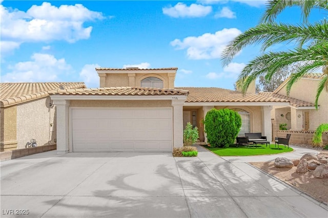 mediterranean / spanish-style house featuring stucco siding, a tiled roof, concrete driveway, and a garage