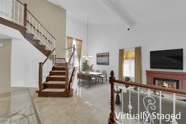 living area with beamed ceiling, stairway, tile patterned flooring, a brick fireplace, and a towering ceiling