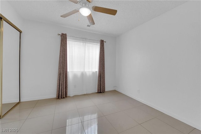 tiled empty room with baseboards, visible vents, a textured ceiling, and ceiling fan