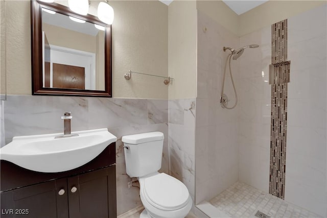 full bathroom featuring a tile shower, toilet, vanity, and tile walls