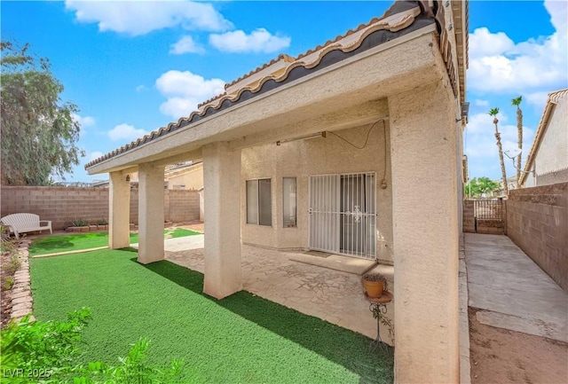 back of house with a patio, a yard, a fenced backyard, stucco siding, and a tiled roof