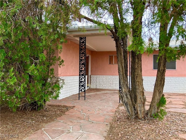 doorway to property with brick siding and stucco siding