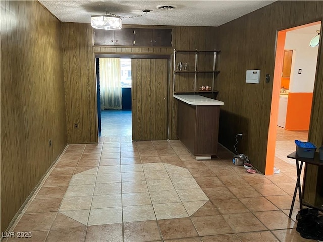 kitchen featuring open shelves, wooden walls, washer / dryer, and a textured ceiling