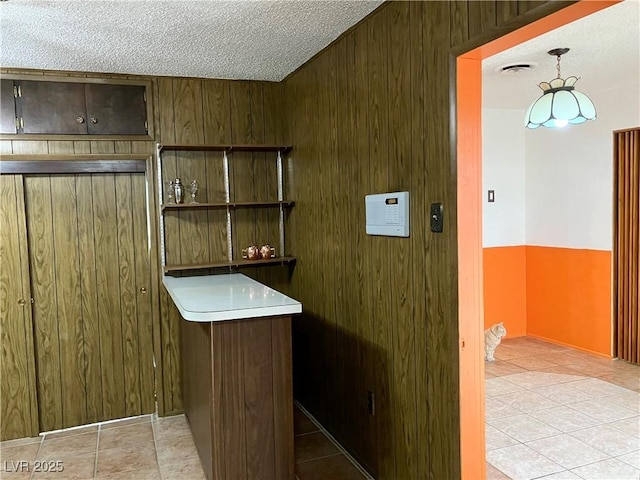 kitchen with tile patterned floors, wooden walls, and a textured ceiling