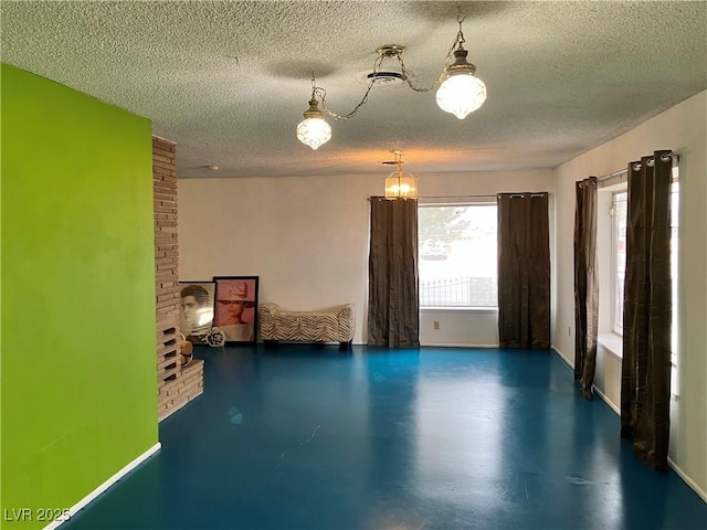 interior space with a notable chandelier, a textured ceiling, baseboards, and finished concrete floors