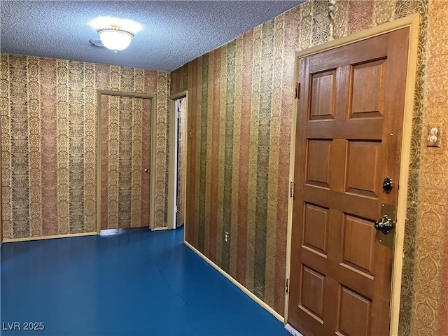 corridor featuring wallpapered walls and a textured ceiling