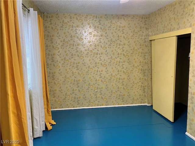 unfurnished bedroom featuring wallpapered walls, a closet, and a textured ceiling