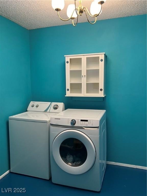 washroom featuring a textured ceiling, laundry area, a chandelier, and washer and clothes dryer