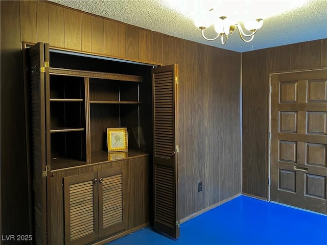 interior details with an inviting chandelier, wood walls, and a textured ceiling