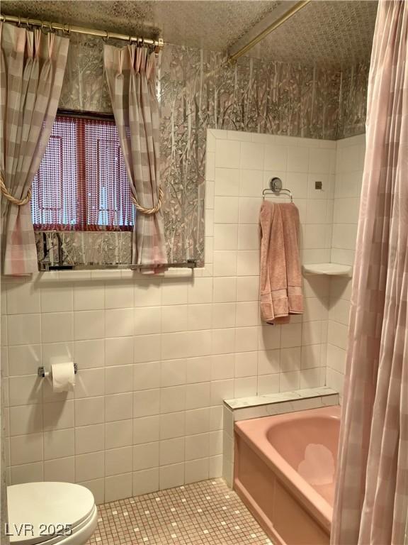 bathroom featuring tile patterned flooring, toilet, and tile walls