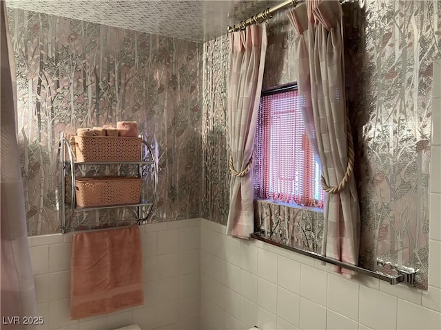 bathroom with tile walls and wallpapered walls