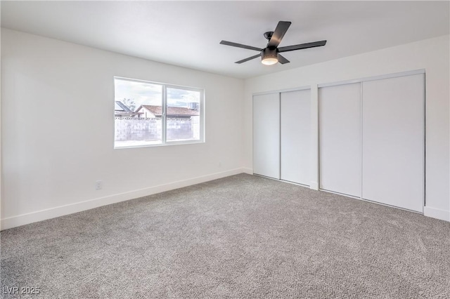 unfurnished bedroom with baseboards, multiple closets, ceiling fan, and carpet flooring