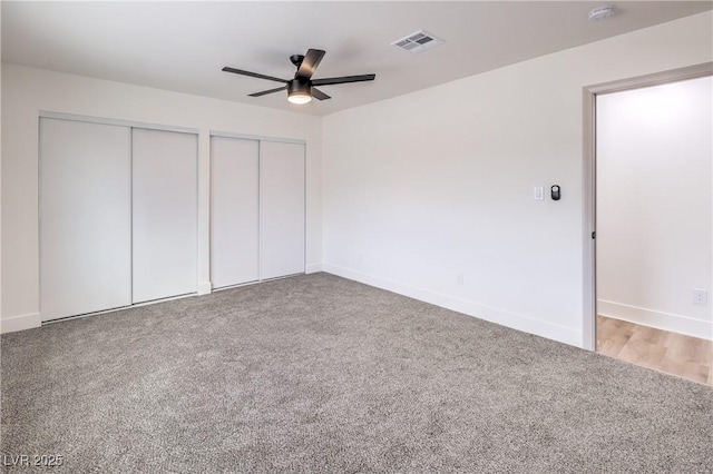 unfurnished bedroom with visible vents, baseboards, multiple closets, ceiling fan, and carpet flooring