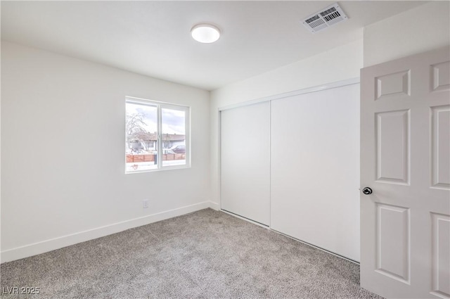 unfurnished bedroom featuring baseboards, visible vents, carpet floors, and a closet