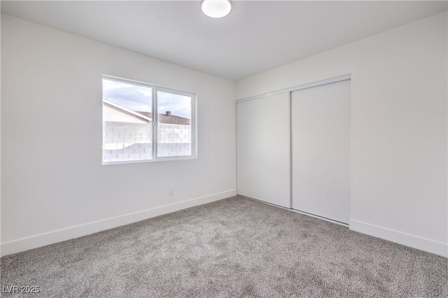 unfurnished bedroom with baseboards, carpet floors, and a closet