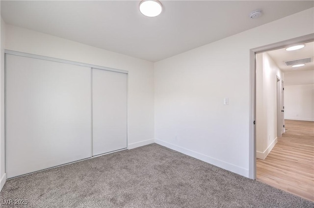 carpeted spare room with visible vents and baseboards